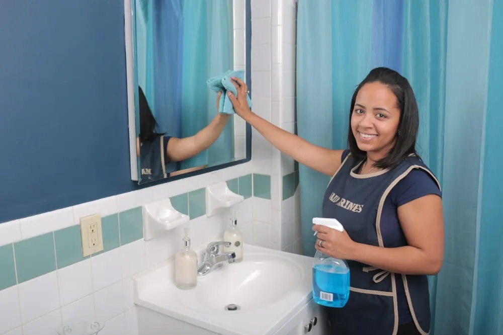 Maid Marines cleaner wiping bathroom mirror